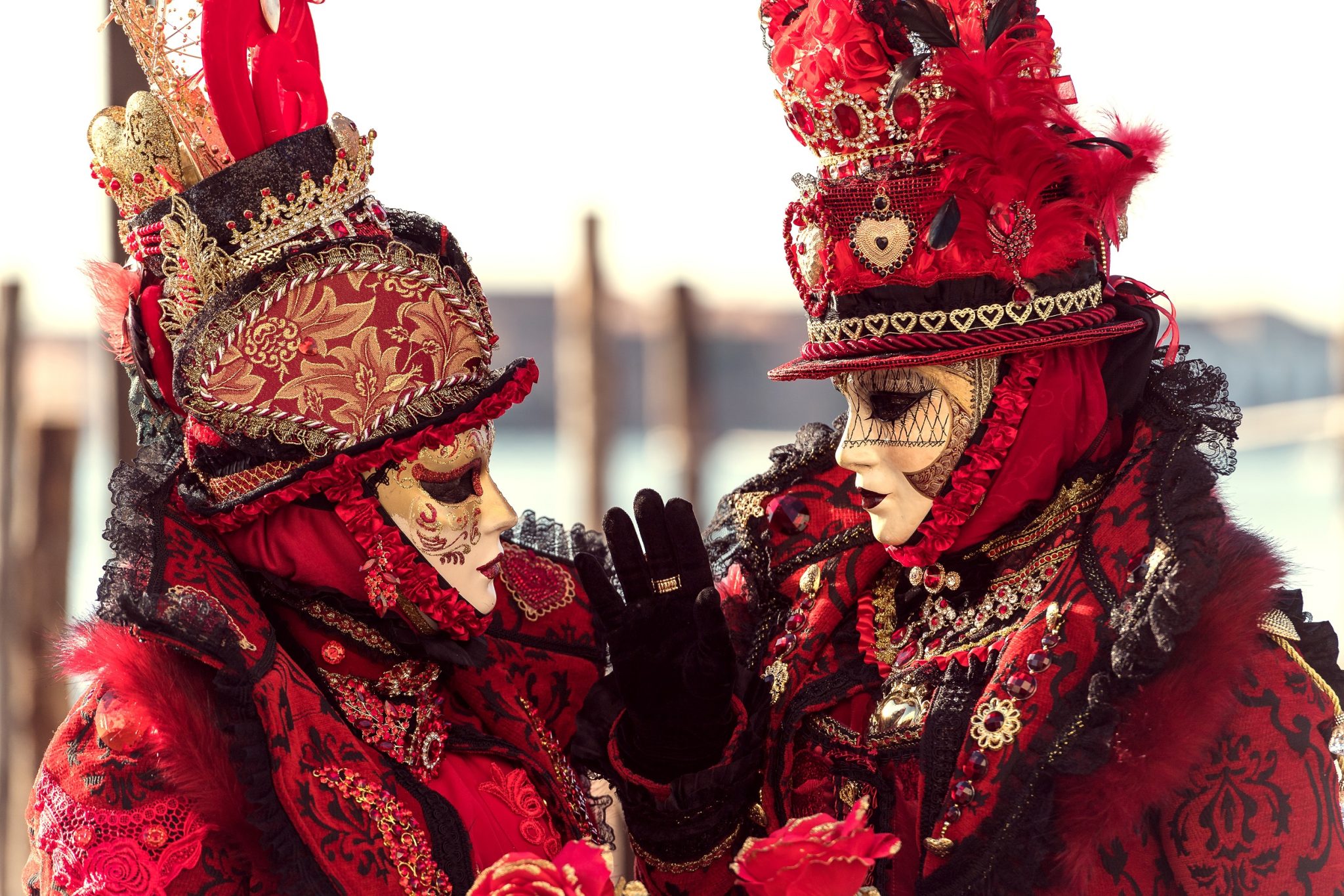 Communicating couple dressed in very detailed red costumes at Carnival in Venice